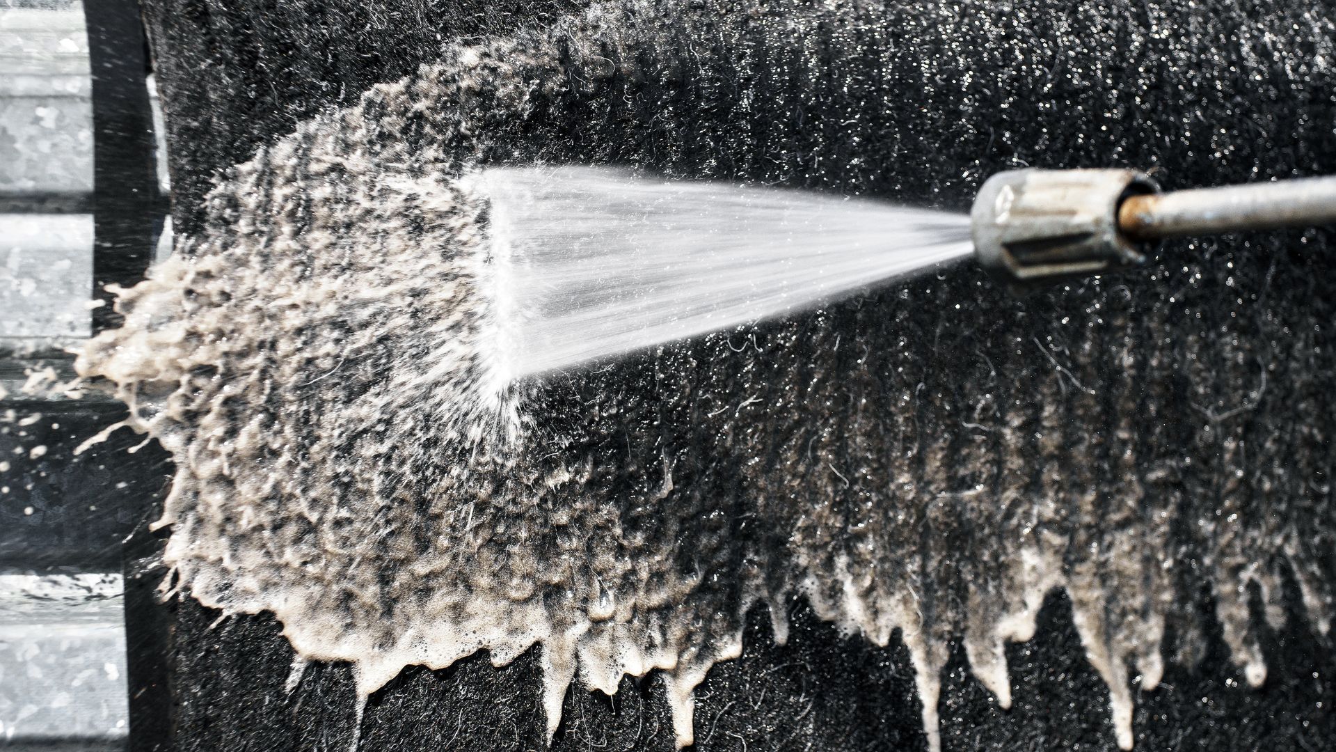 A fire hydrant spewing water onto a sidewalk